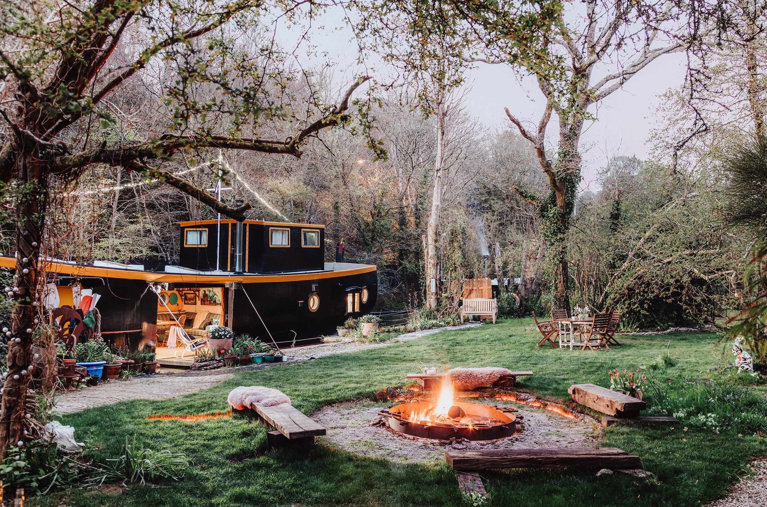 a black house boat moored next to a fire pit