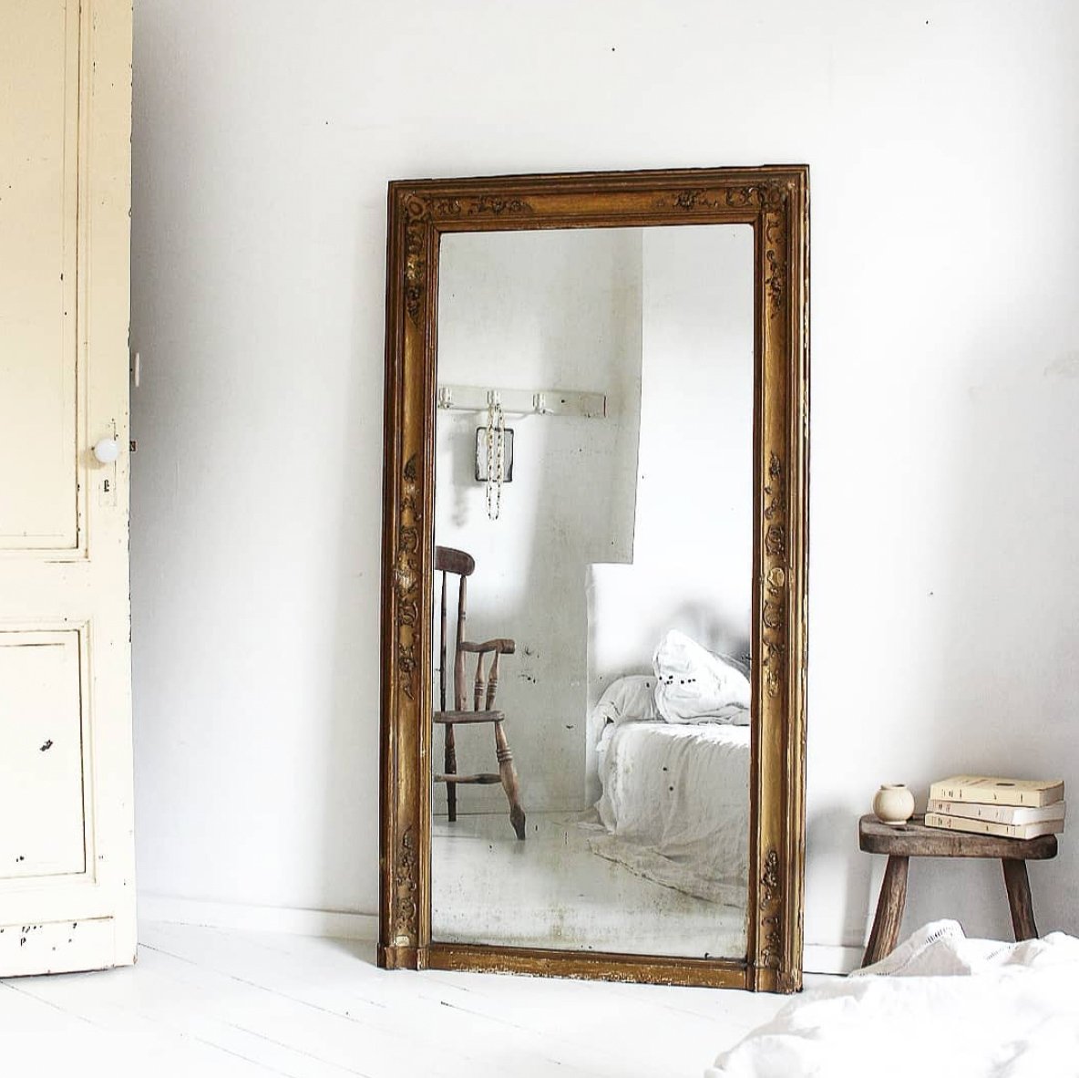 White interior with reflection in gilded mirror of bedroom