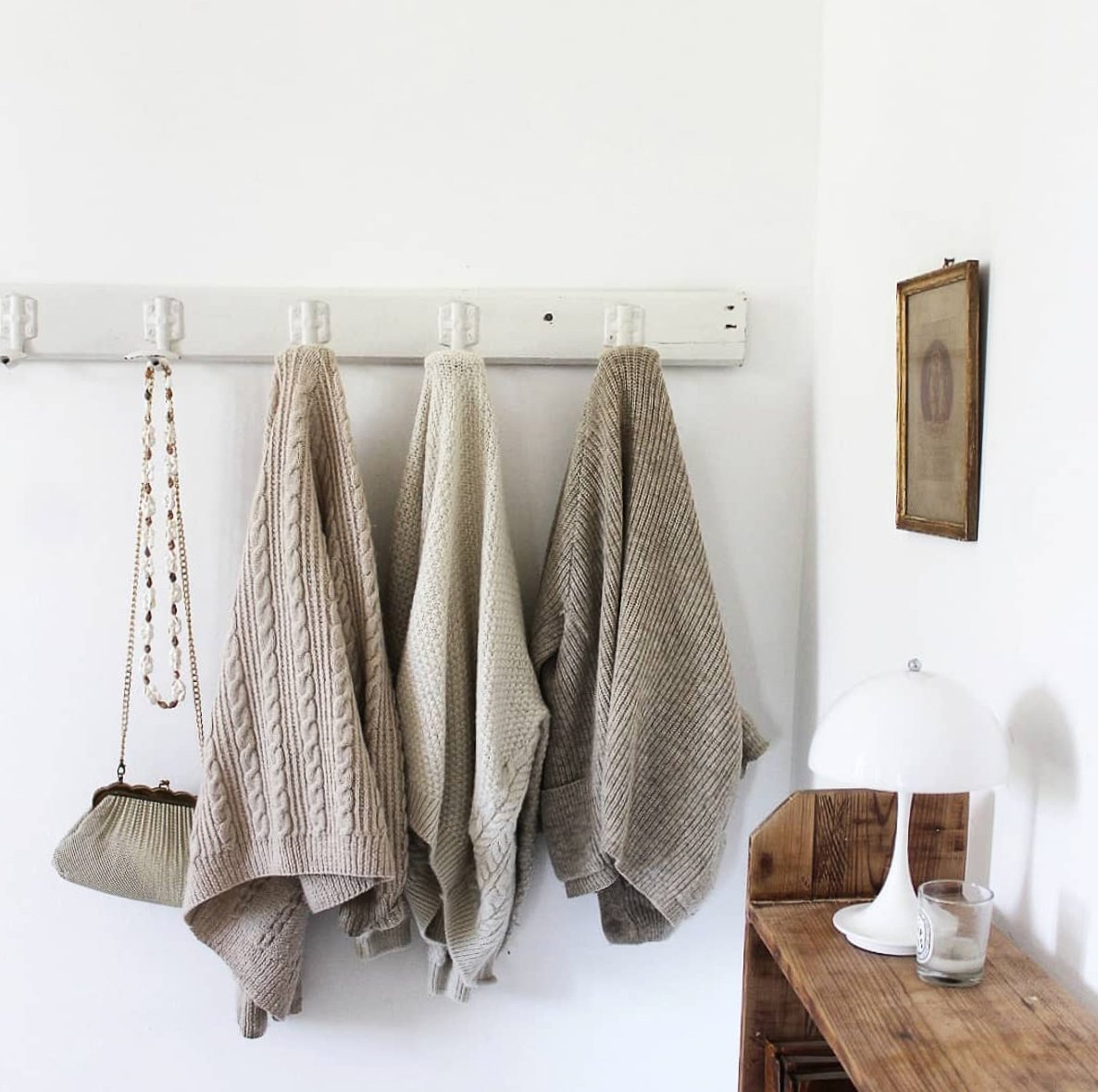 White interior with wall hooks with hanging woollen jumpers