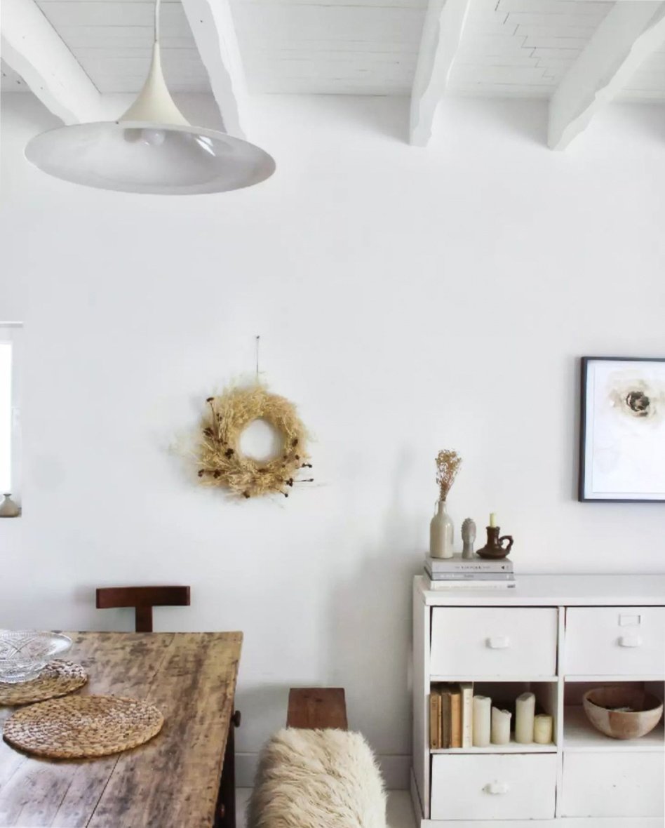 White interior with vintage furniture and dried flower wreath on wall