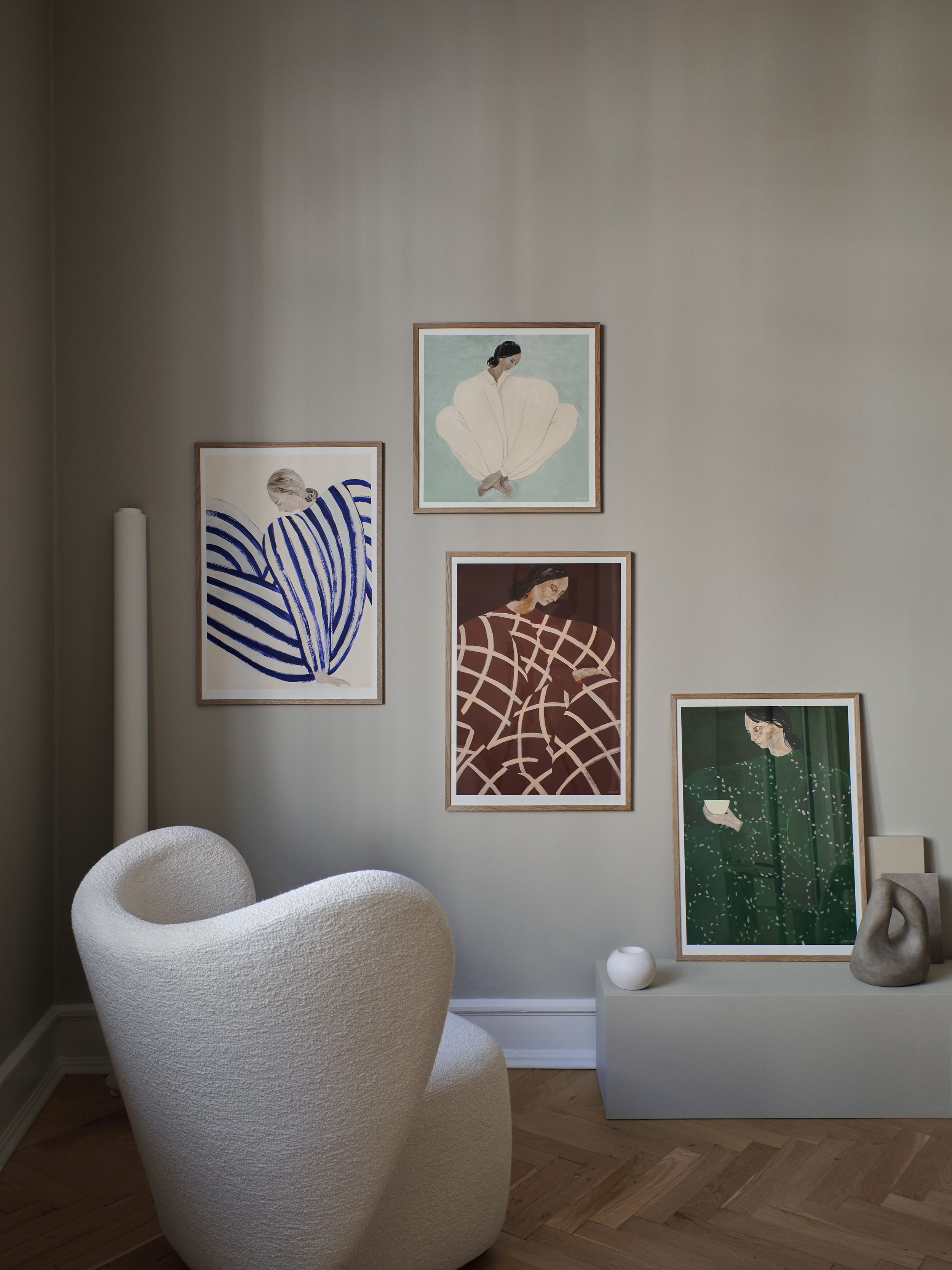 selection of artwork on a wall with a curvaceous chair