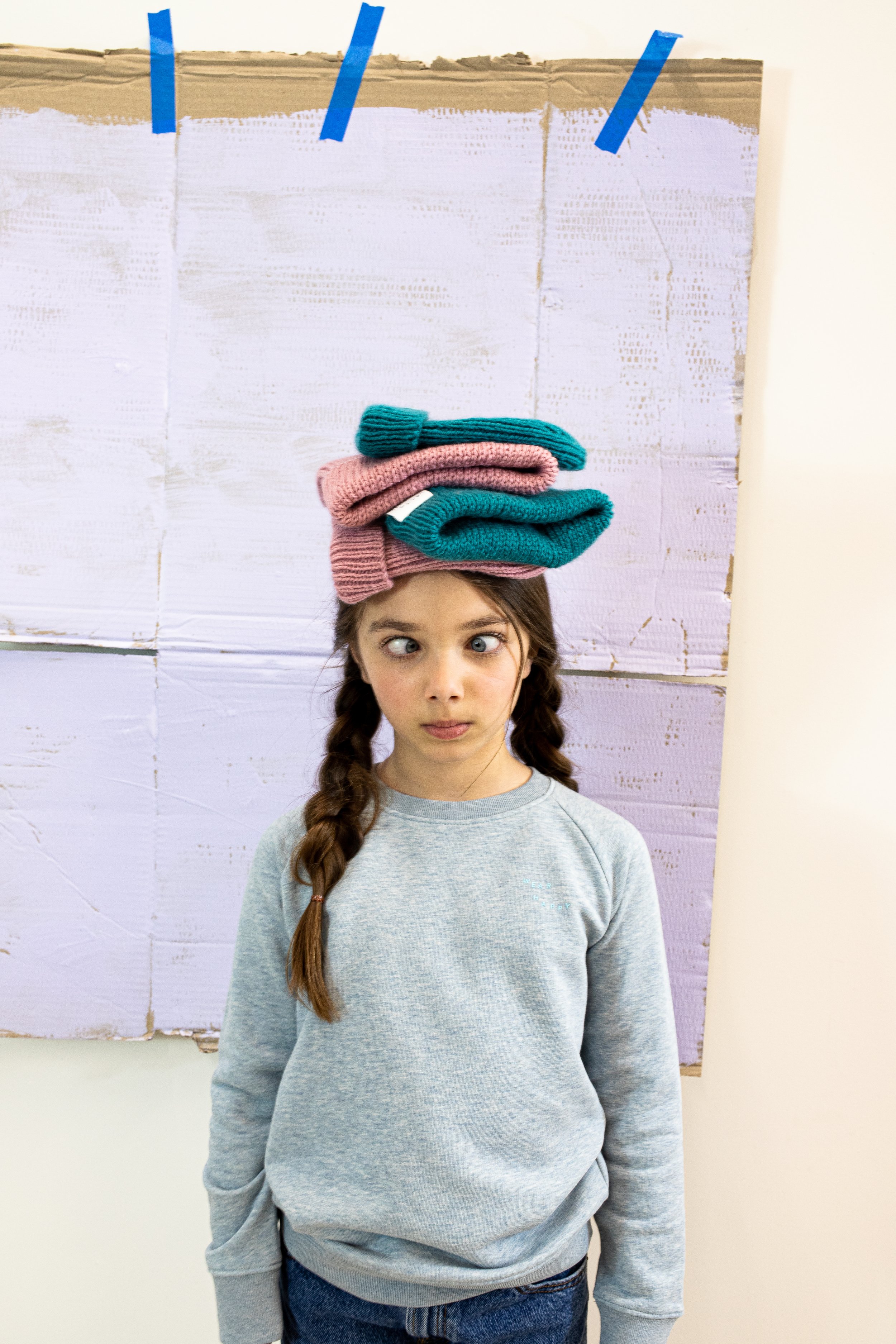 Child model crosses eyes with four Cub and Pudding hats layered on her head