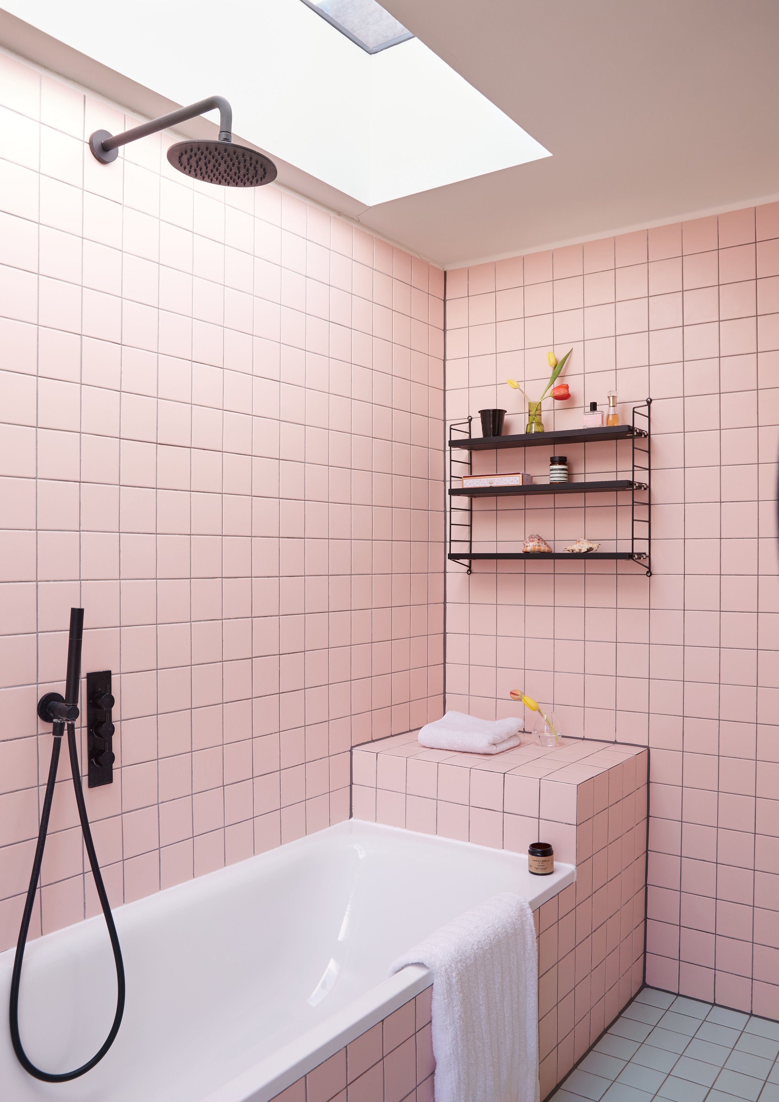 Pink tiled bathroom with black shower fittings and shelving