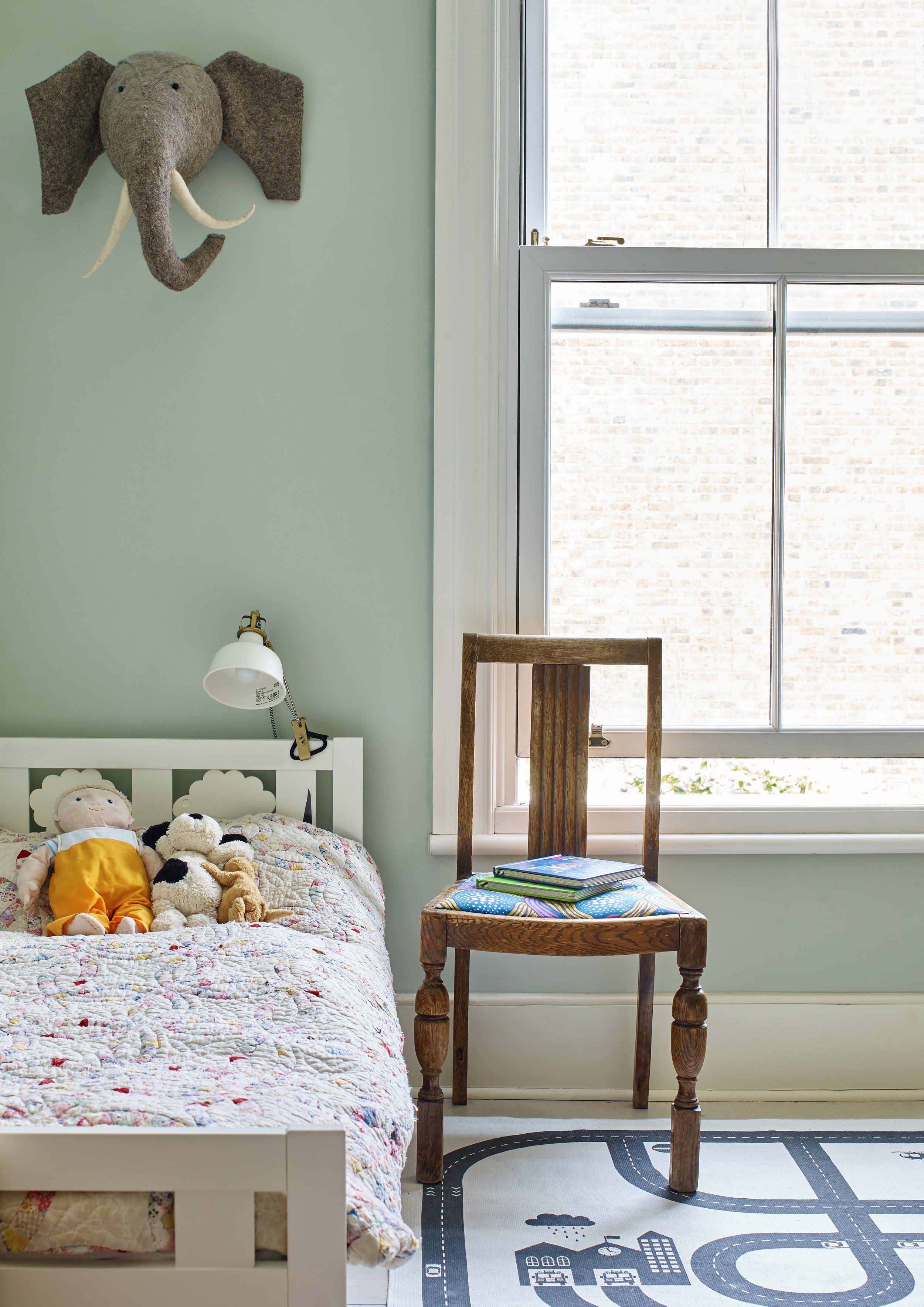 Child's bedroom with pale green paint and elephant head on wall