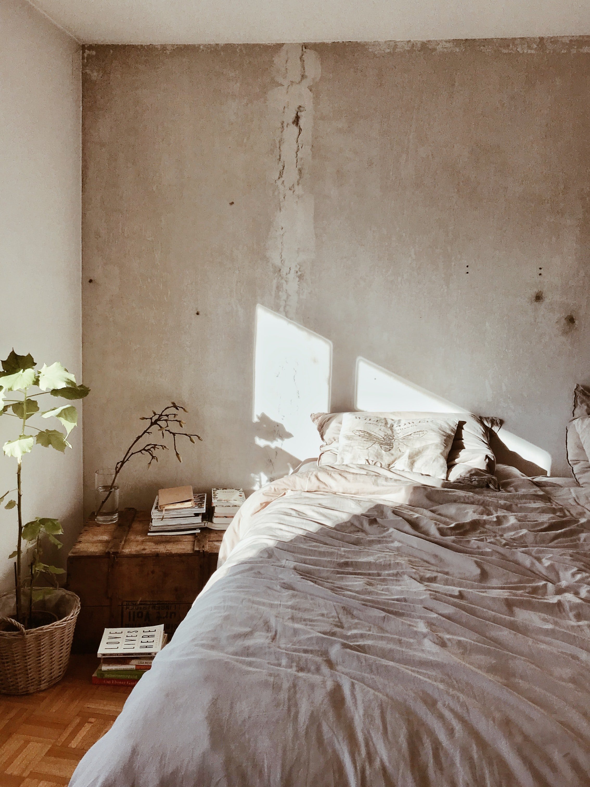 image of messy bed with bare plaster wall behind