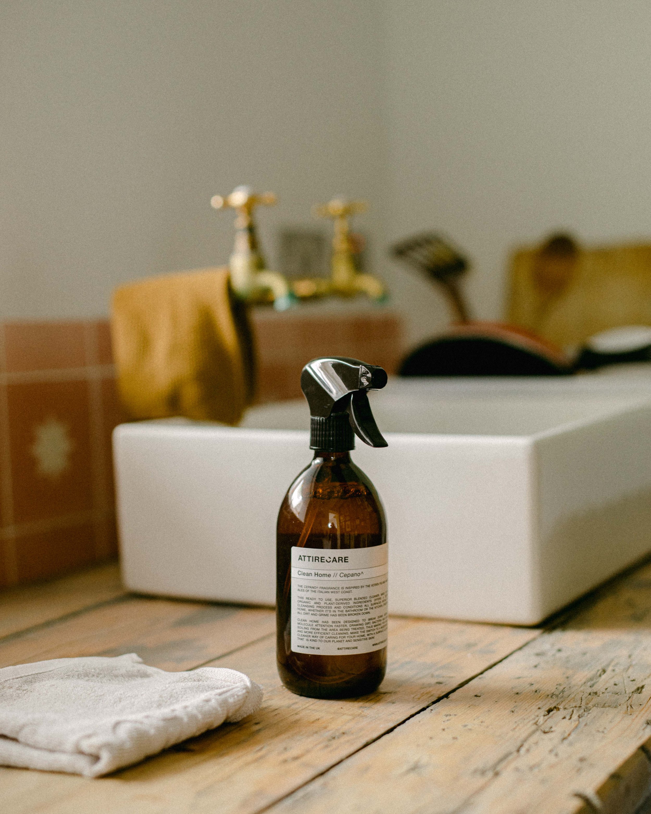 amber glass bottle of cleaning spray by Attirecare, by a sink