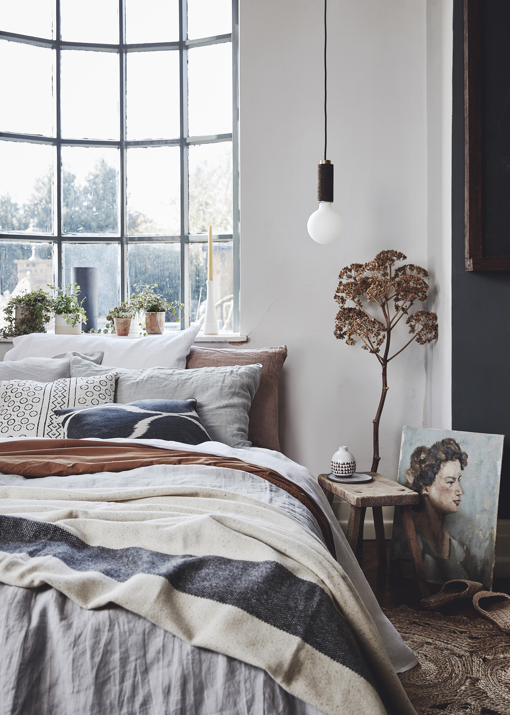 Grey 100% linen bedding – Soak and Sleep; Terracotta organic cotton bedding – H&M Home; Seagrass rug – Armadillo; Handwoven grass slippers – Yonder Living; Blanket – The London Cloth Company; Lighting – Nove Lighting; Cushion in foreground – Por…