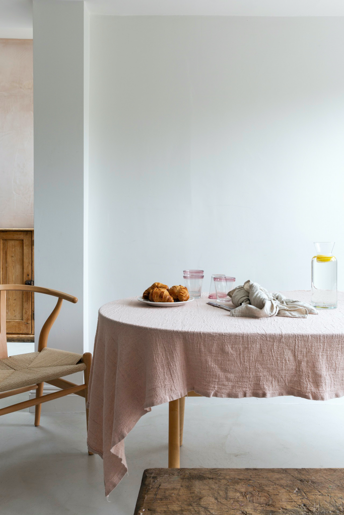 Dining table with pink table cloth and wishbone chair