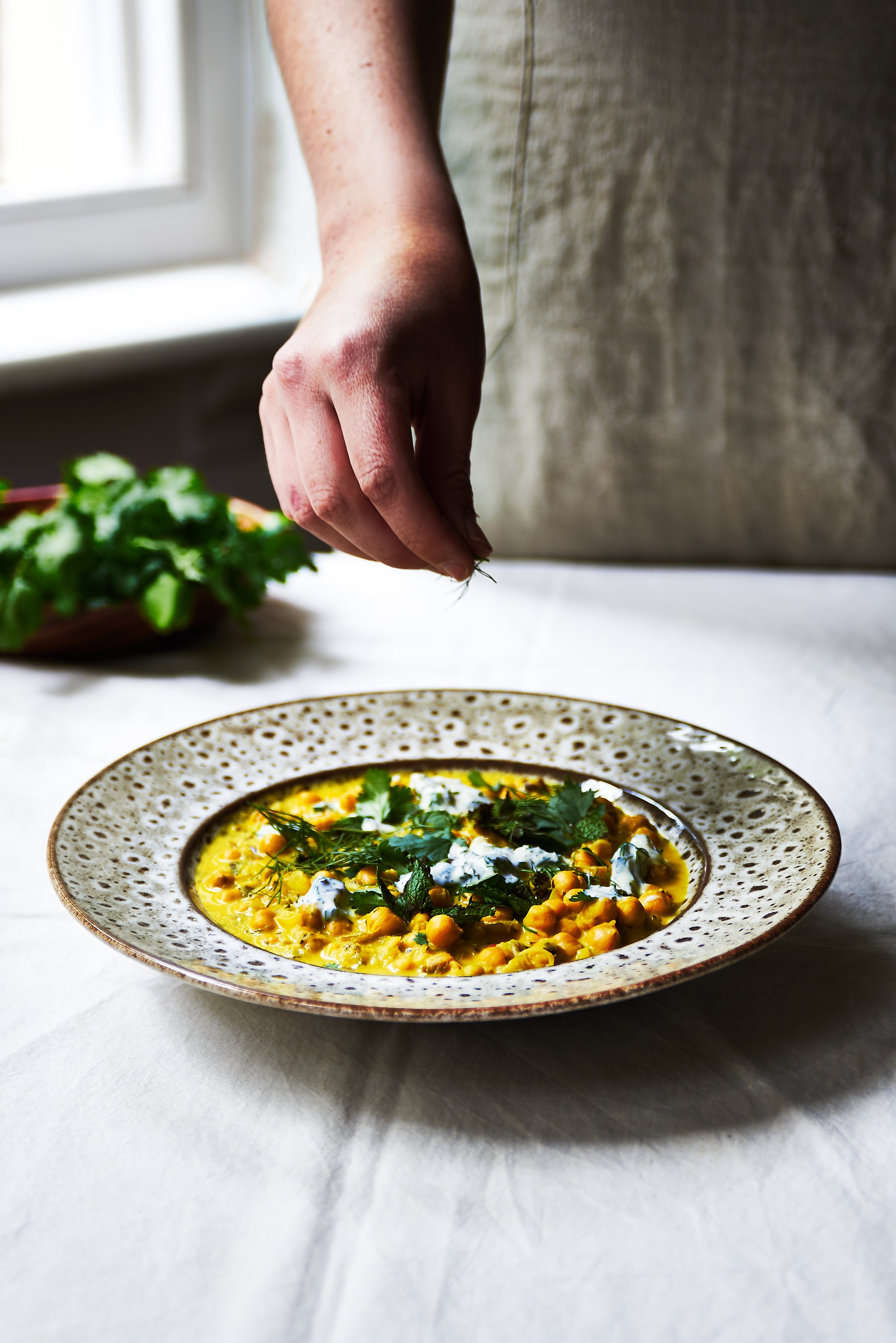 Courgette and chickpea stew in a bowl on white tableclothed table