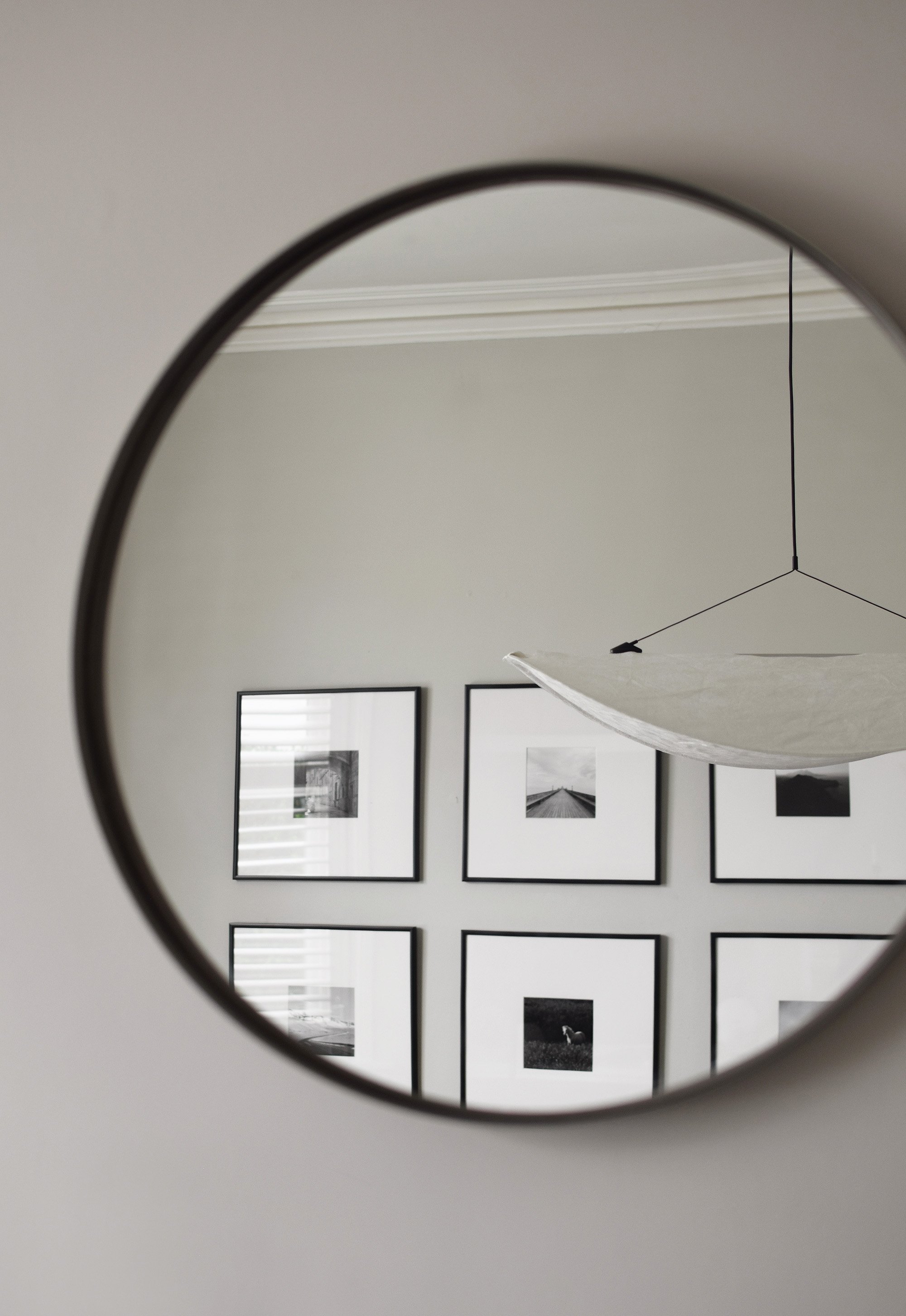 Round black mirror and photos inside the minimalist home of Abi Dare, of These Four Walls Blog