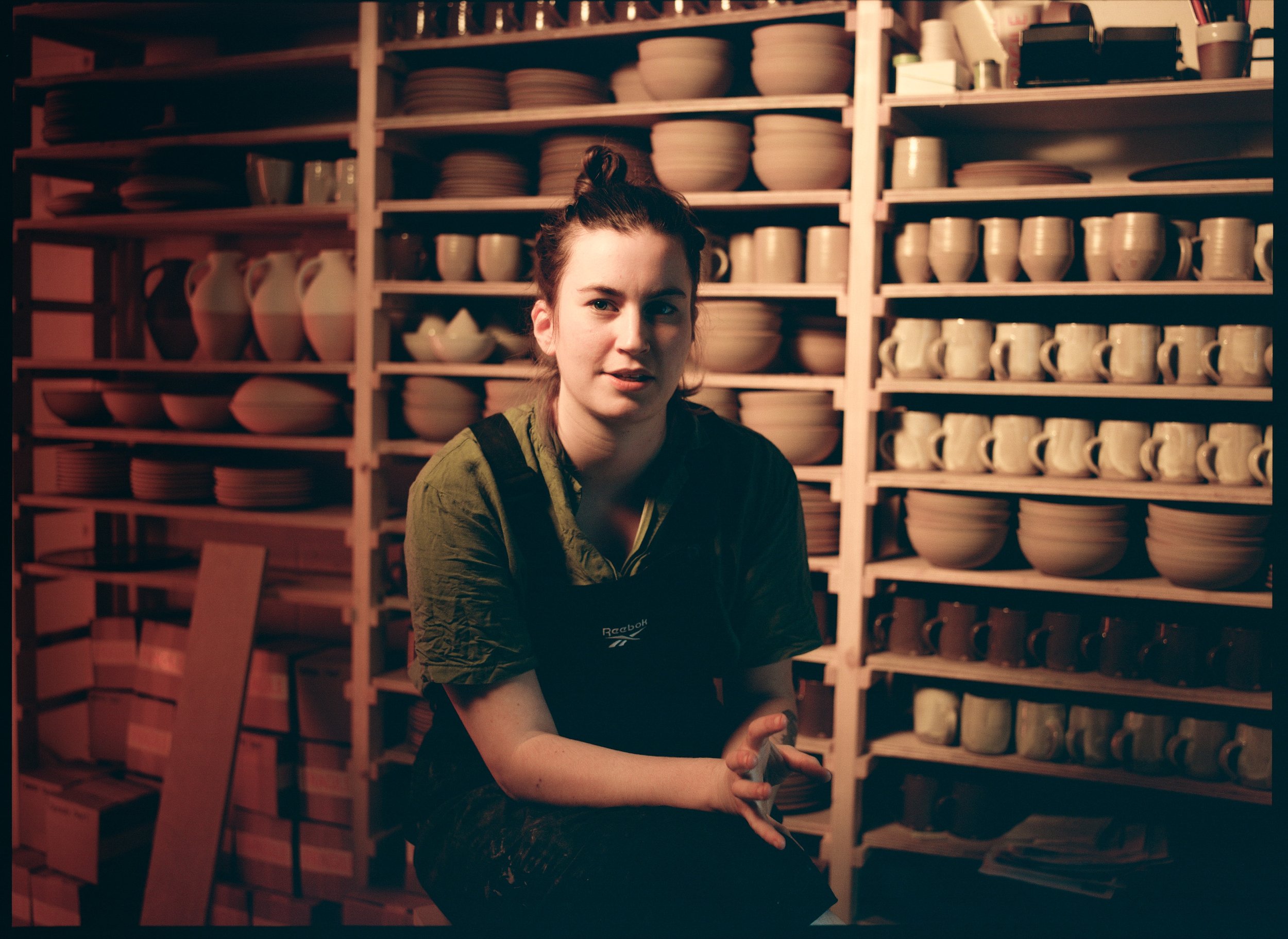Ceramicist Lily Pearmain in her studio with shelves of her work