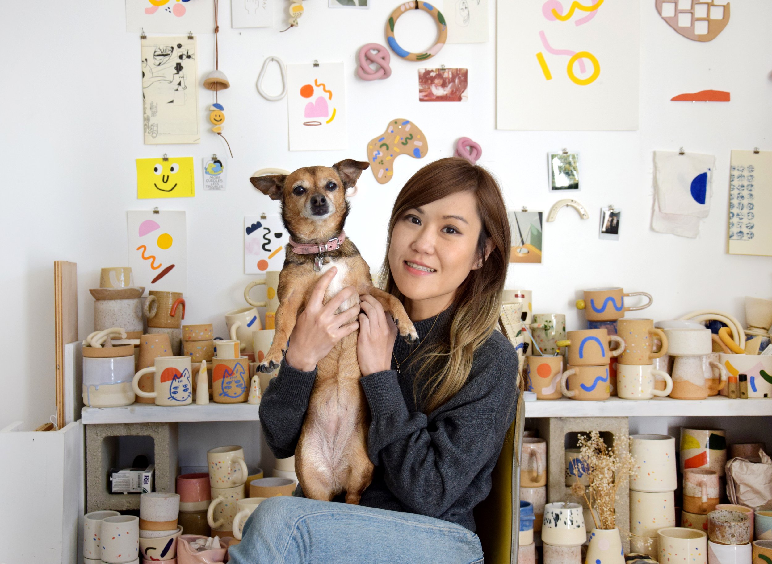 Carrie Lau of O-M Ceramics holding her dog in her studio