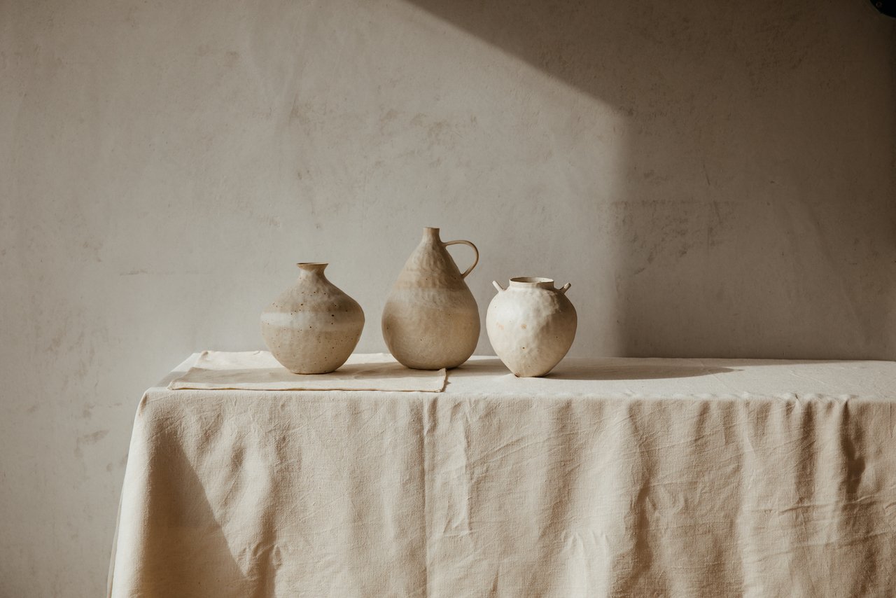 Natural ceramics on a tableclothed table by Toro Studio
