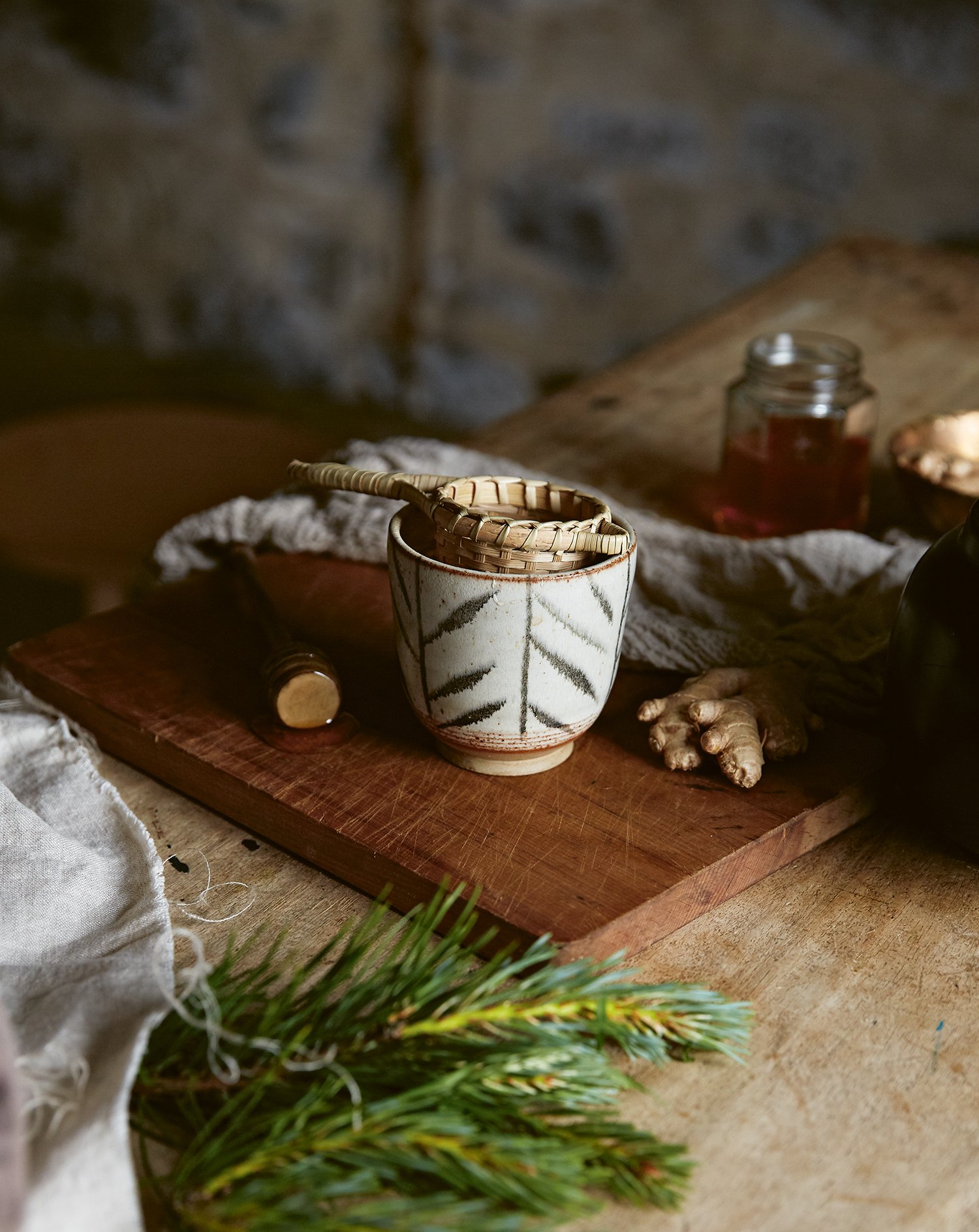 rustic ceramic cup with woven tea strainer on a kitchen table