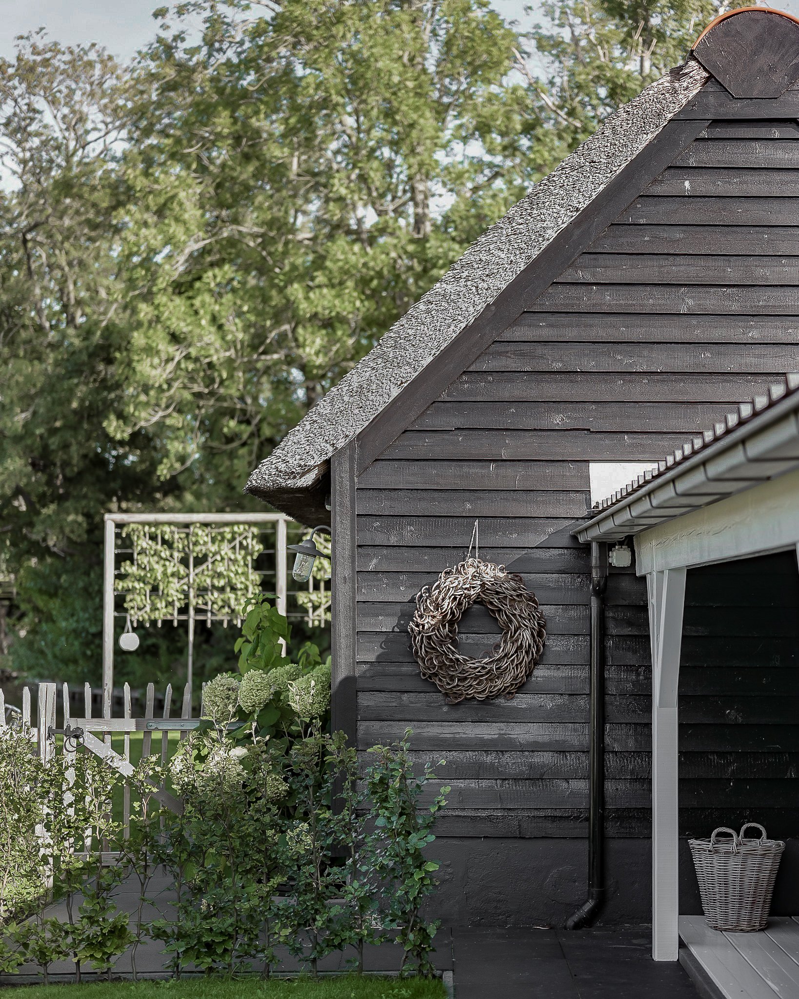 black wooden exterior with natural wreath hanging on wall