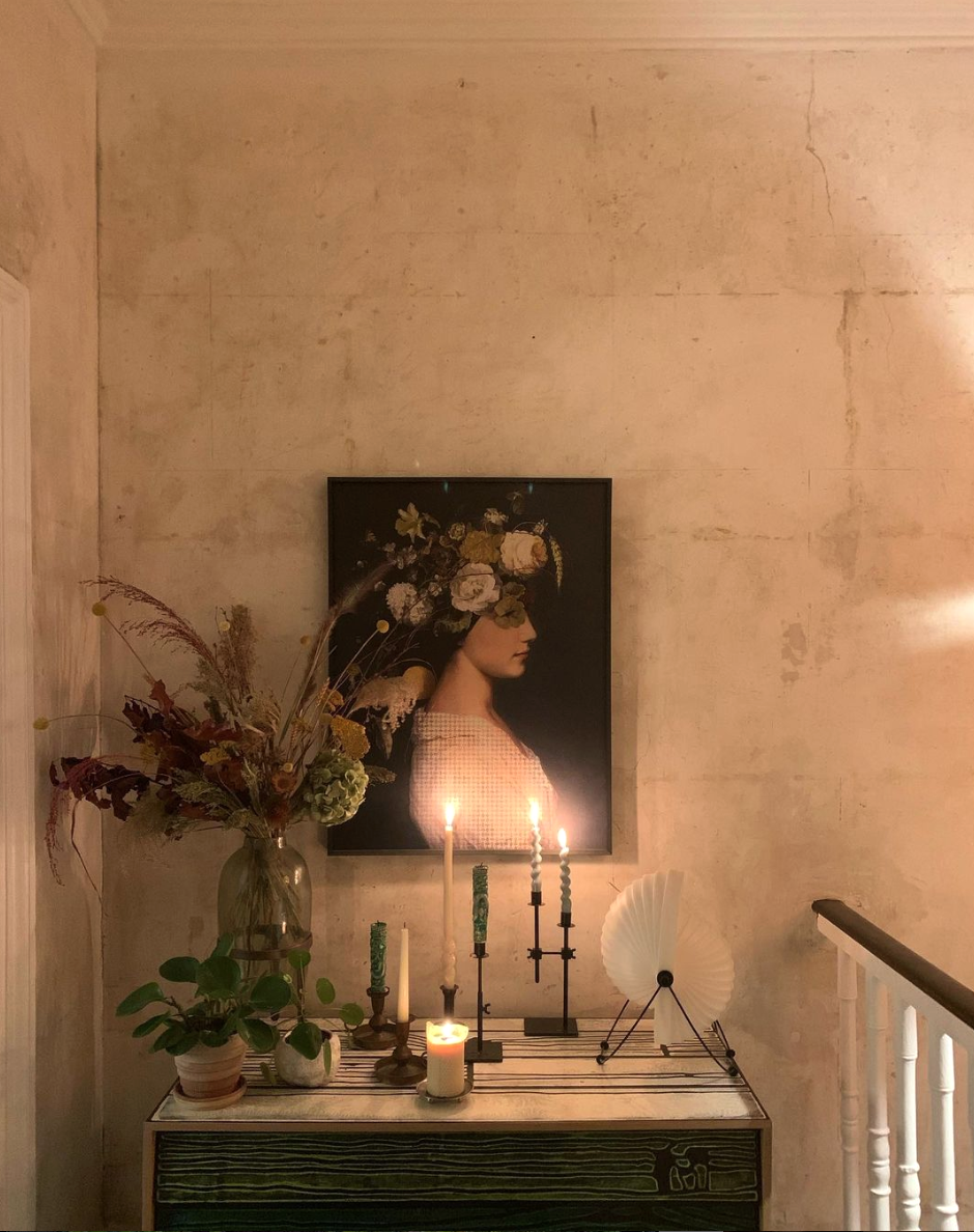 Bare plaster walls, with vintage portrait painting and candles