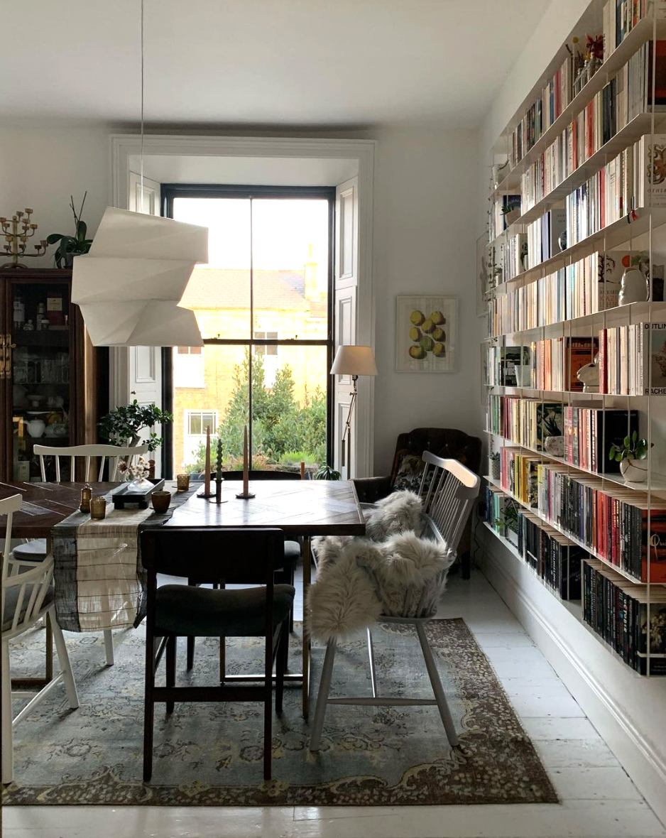 Dining table with mismatched chairs and a wall of books
