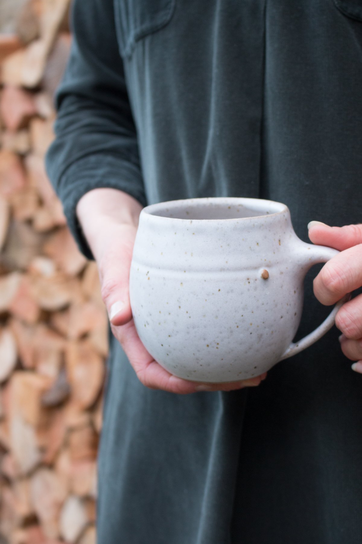 Maker Katie Coston of Illyria Pottery holds her homemade ceramic mugs
