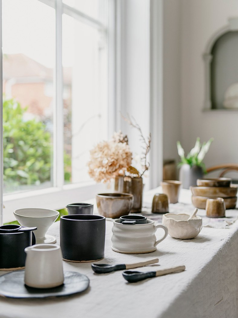 Collection of ceramics on table beside a window