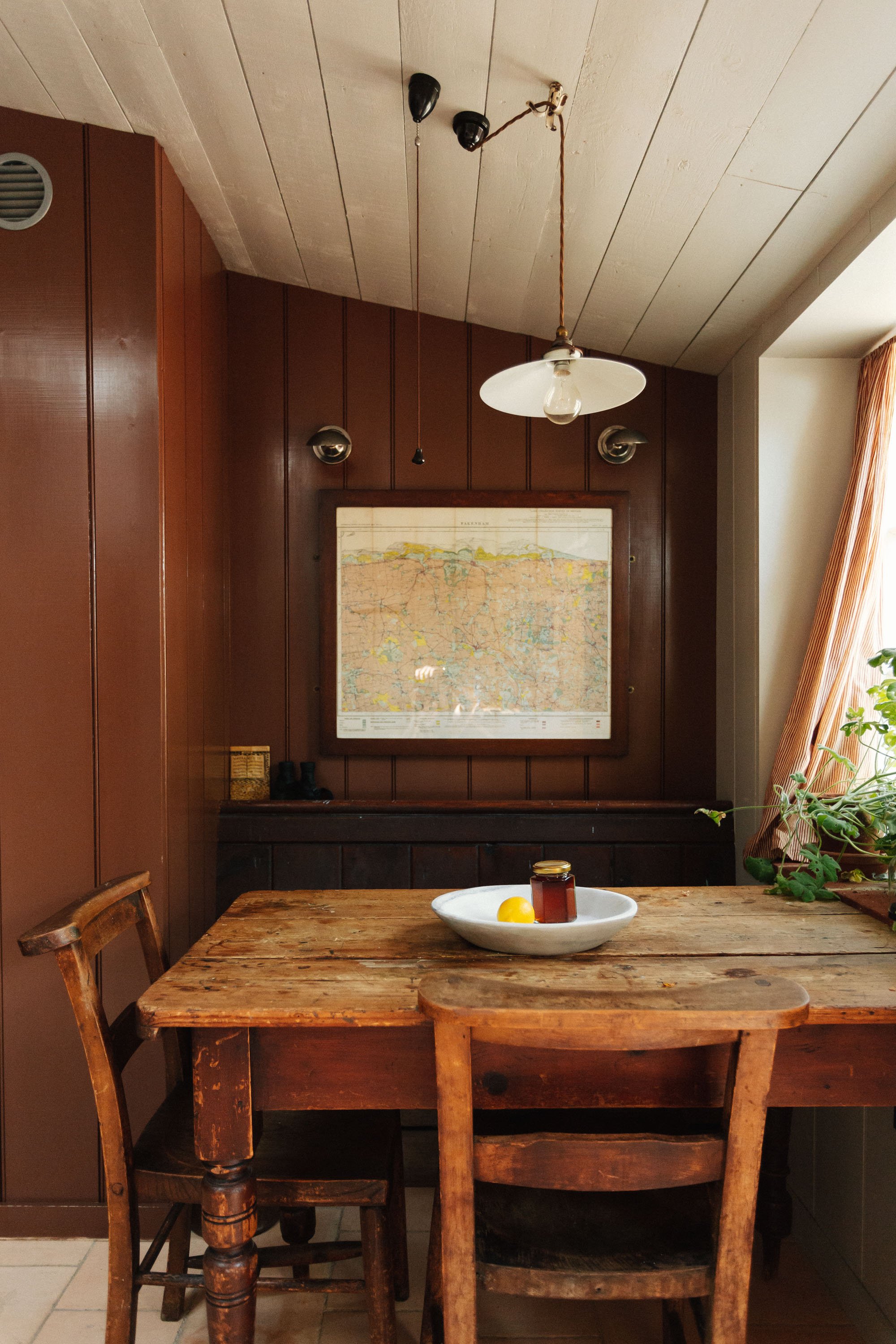 Cosy kitchen table nook with wood clad walls painted in brown