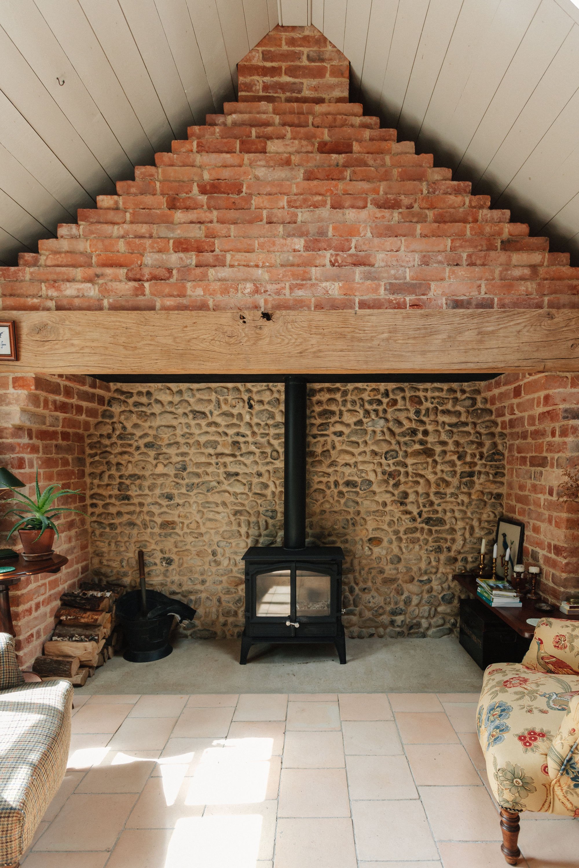 exposred brick wall fireplace with wood burning stove in a cottage