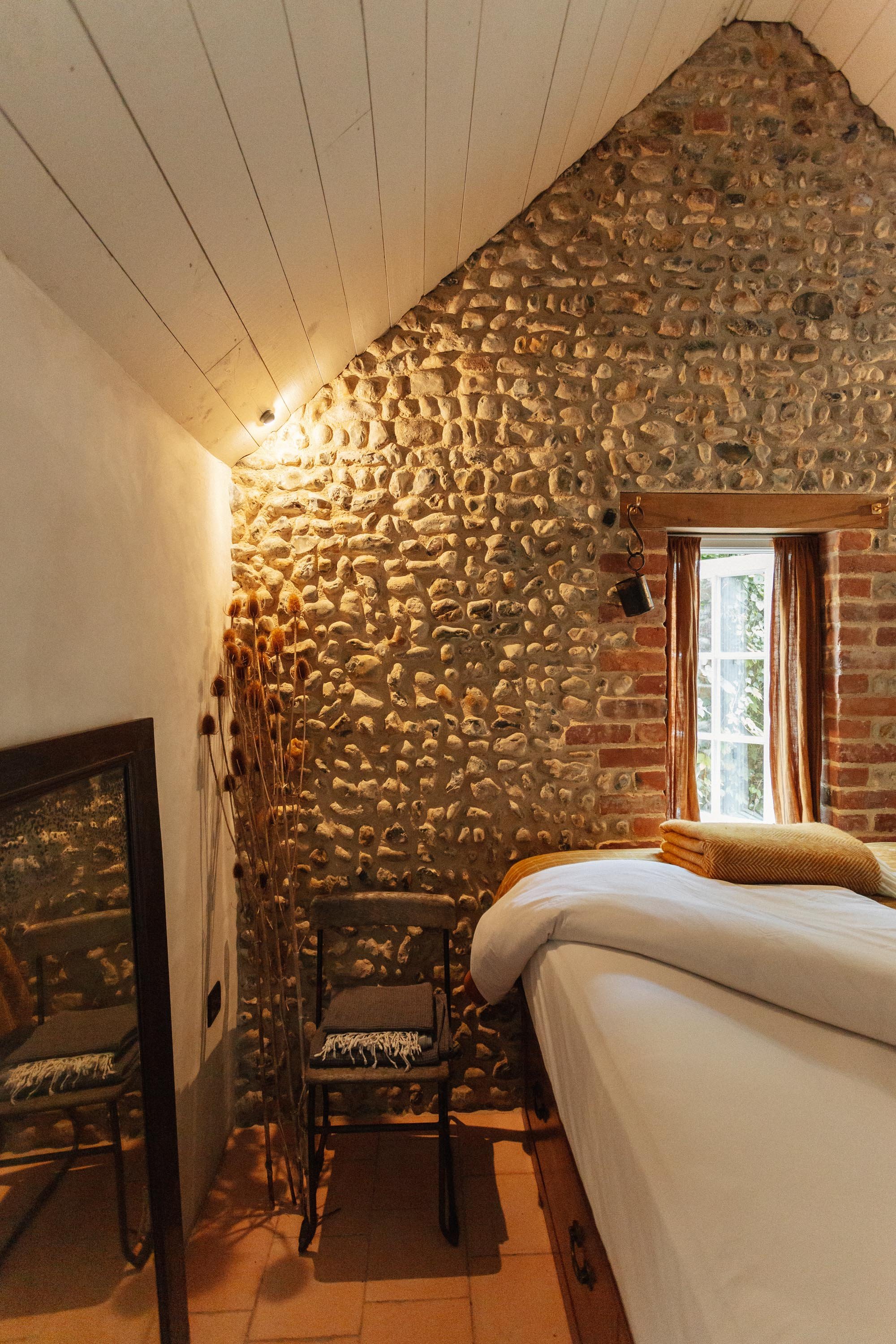 corner of cottage bedroom with flint wall