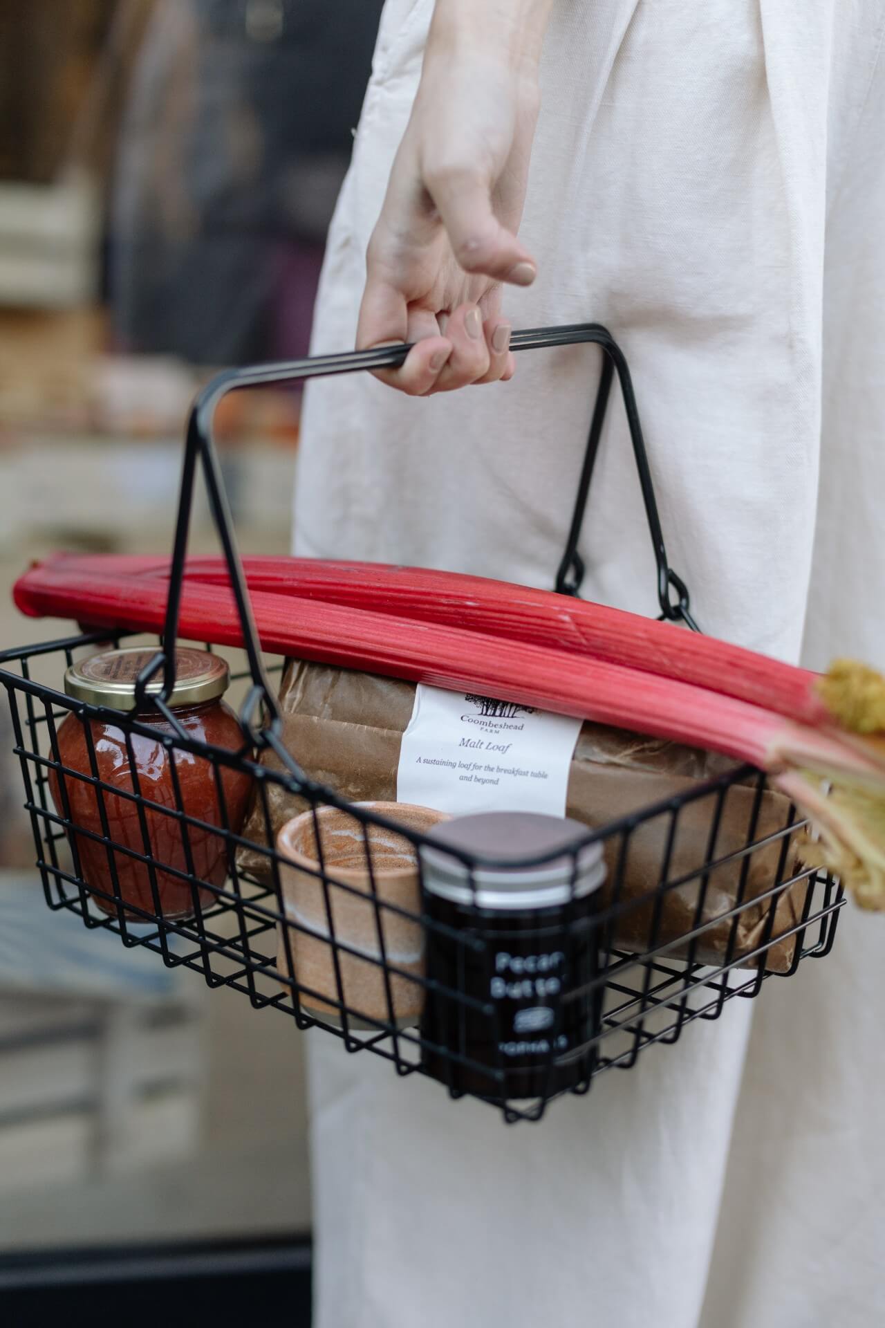 Fresh artisanal bread and rhubarb, sauces and chutneys in black wire basket inside Another Pantry pop up shop