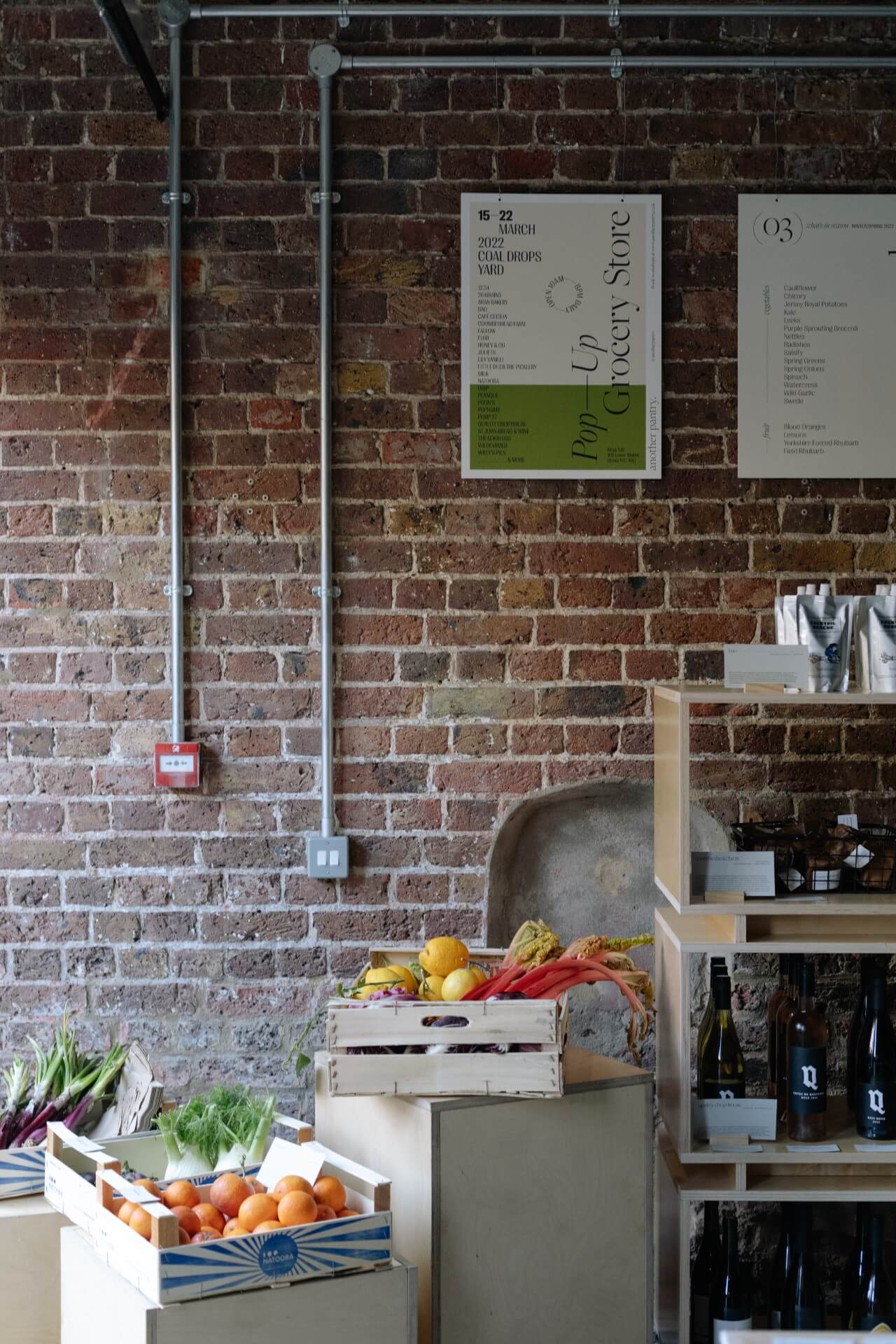 Independent Another Pantry food pop up shop in London with fresh fruit and vegetables on light wooden shelves and exposed brickwork