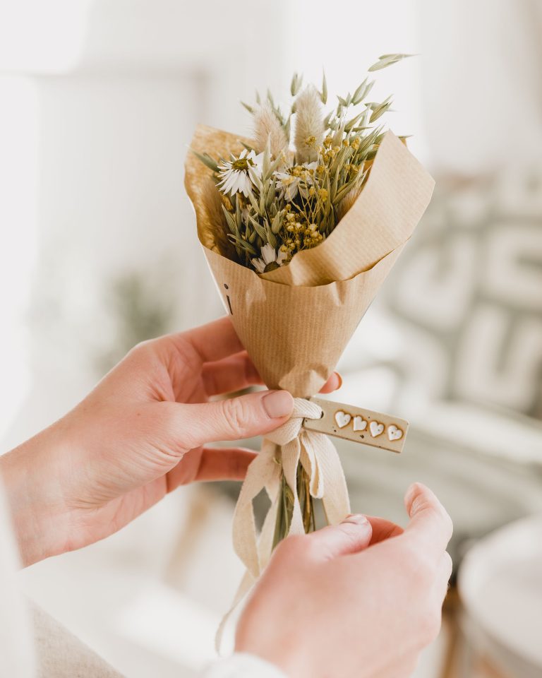 posy of dried flowers wrapped in brown paper with ceramic tag by Teppi