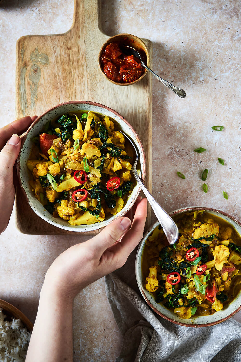 hands holding Cauliflower and lentil curry in a bowl 