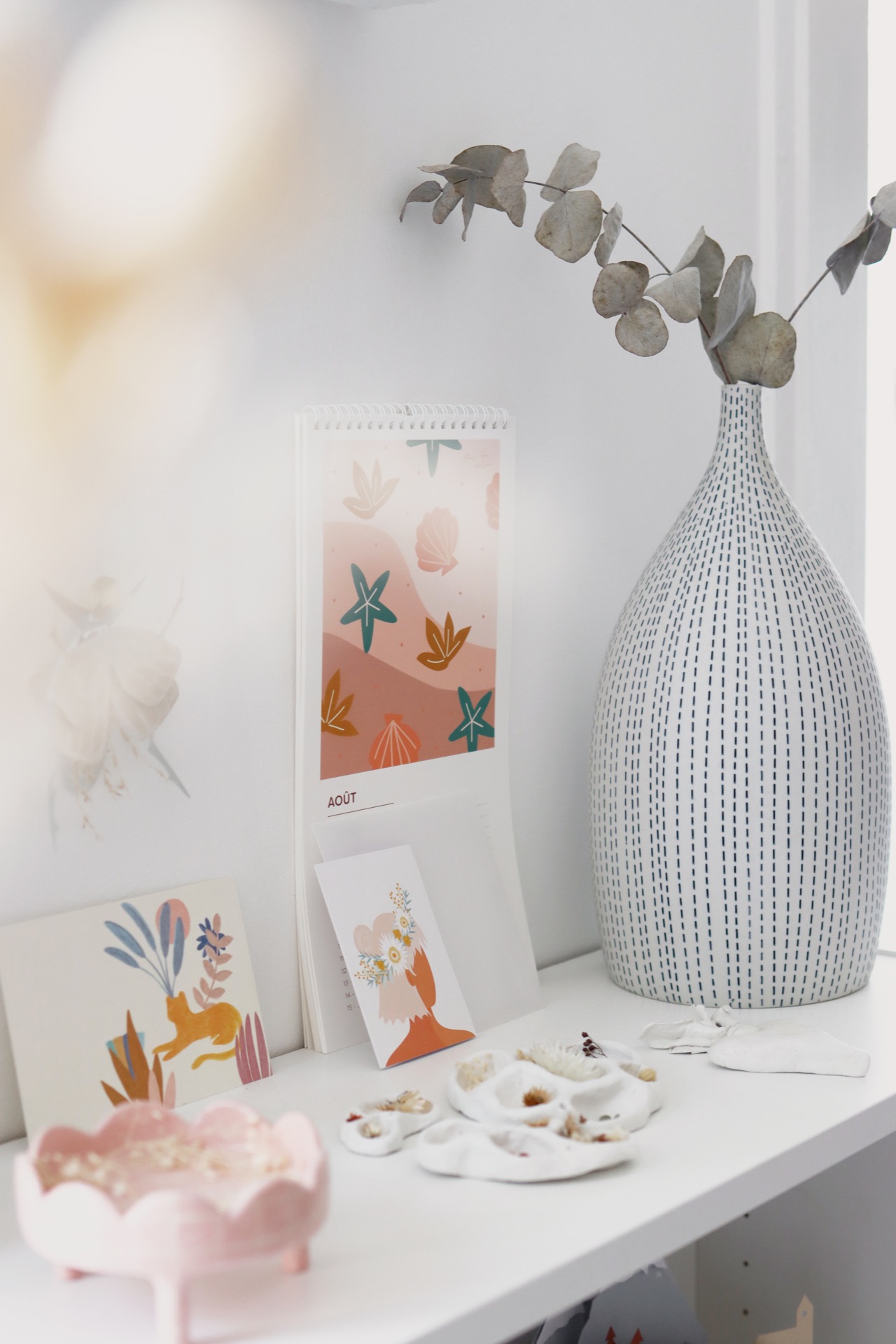 colourful objects and postcards styled on a white shelf