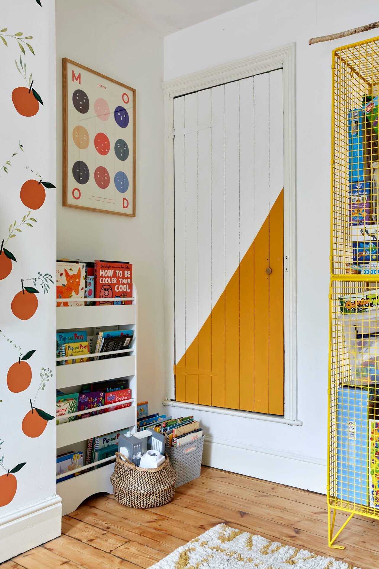 Childs bedroom with peaches wallpaper and a cupboard door painted with a diagonal panel of mustard yellow