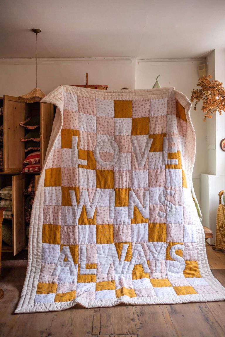 Pink yellow and white patchwork quilt, with the words LOVE WINS ALWAYS by projektityyny