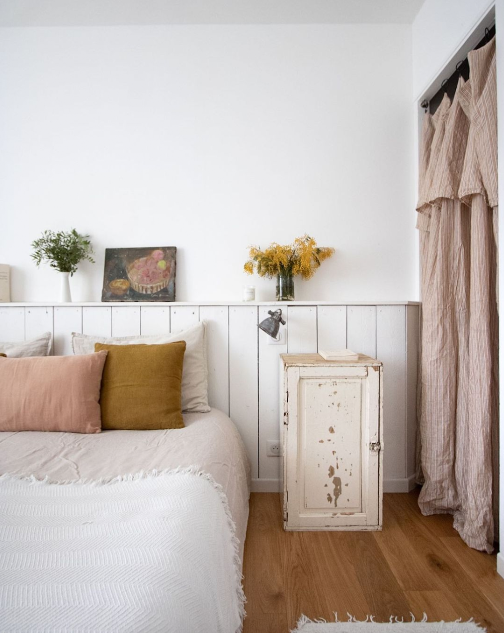 light and bright bedroom with vintage furniture and wood panelling as head board. 