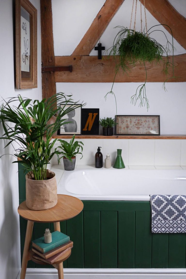 White bathroom with wooden beams and green panelled bath - home of Laura Jenkinson of Ticking Stripe Home