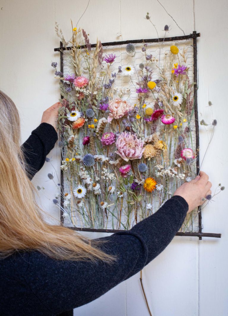 Sustainable interior everlasting floral sculpture designer Layla Robinson displaying dried flowers on wall inside her Hay-on-Wye studio