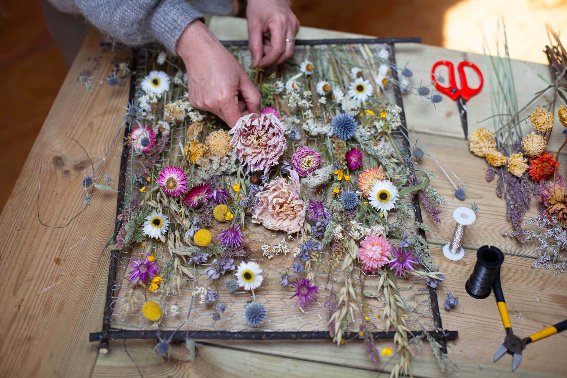 Sustainable interior everlasting floral sculpture designer Layla Robinson creating a dried flower frame inside her Hay-on-Wye studio