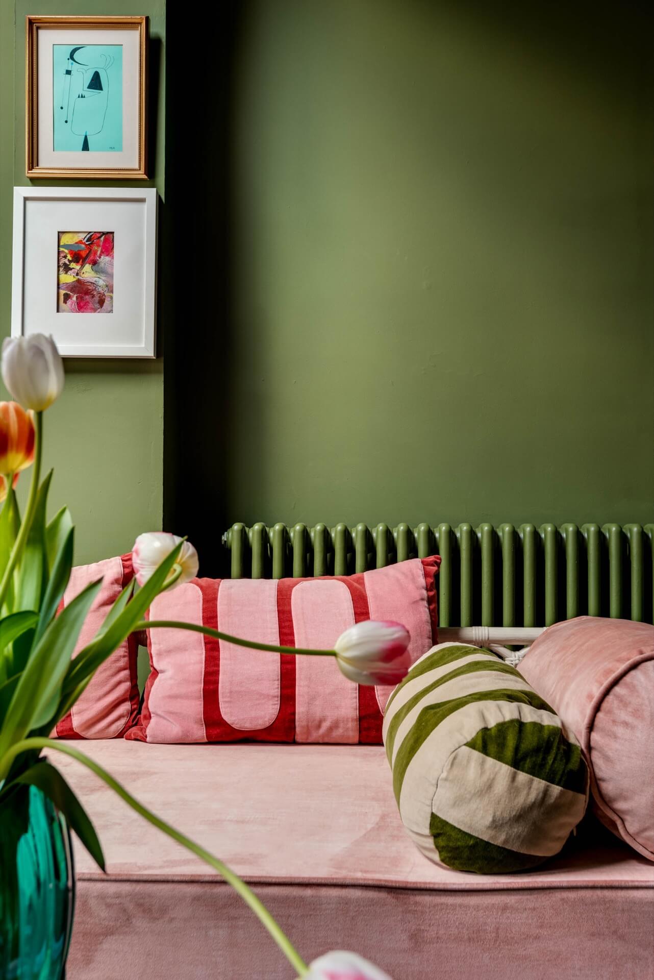 Corner of a green sitting room with colourful cushions