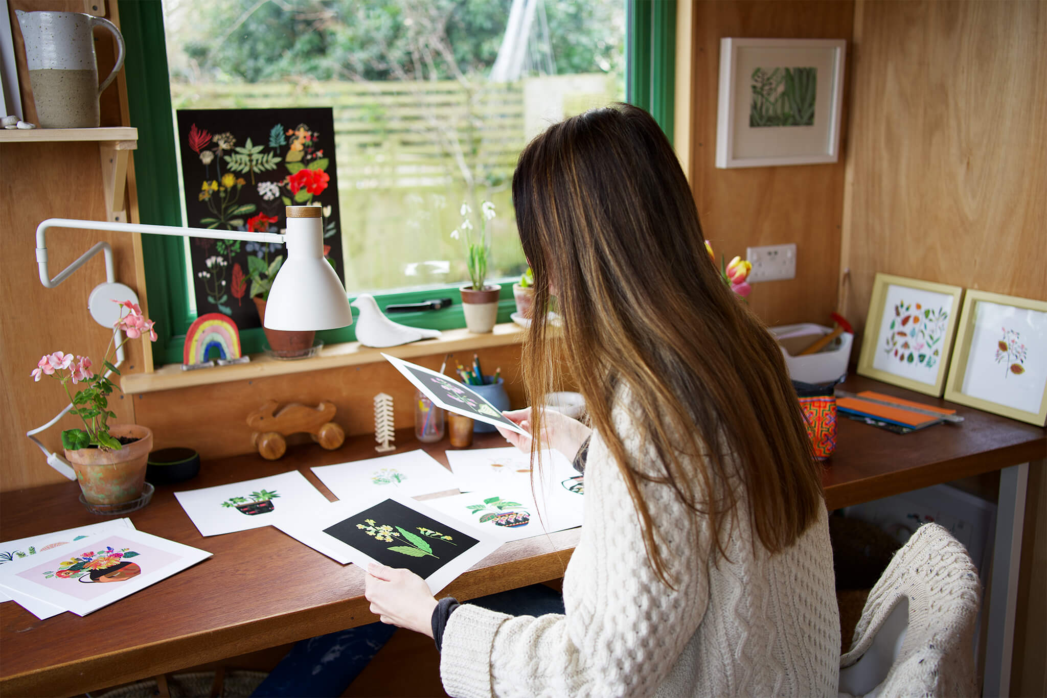 British illustrator Brie Harrison with plant prints inside her wooden studio