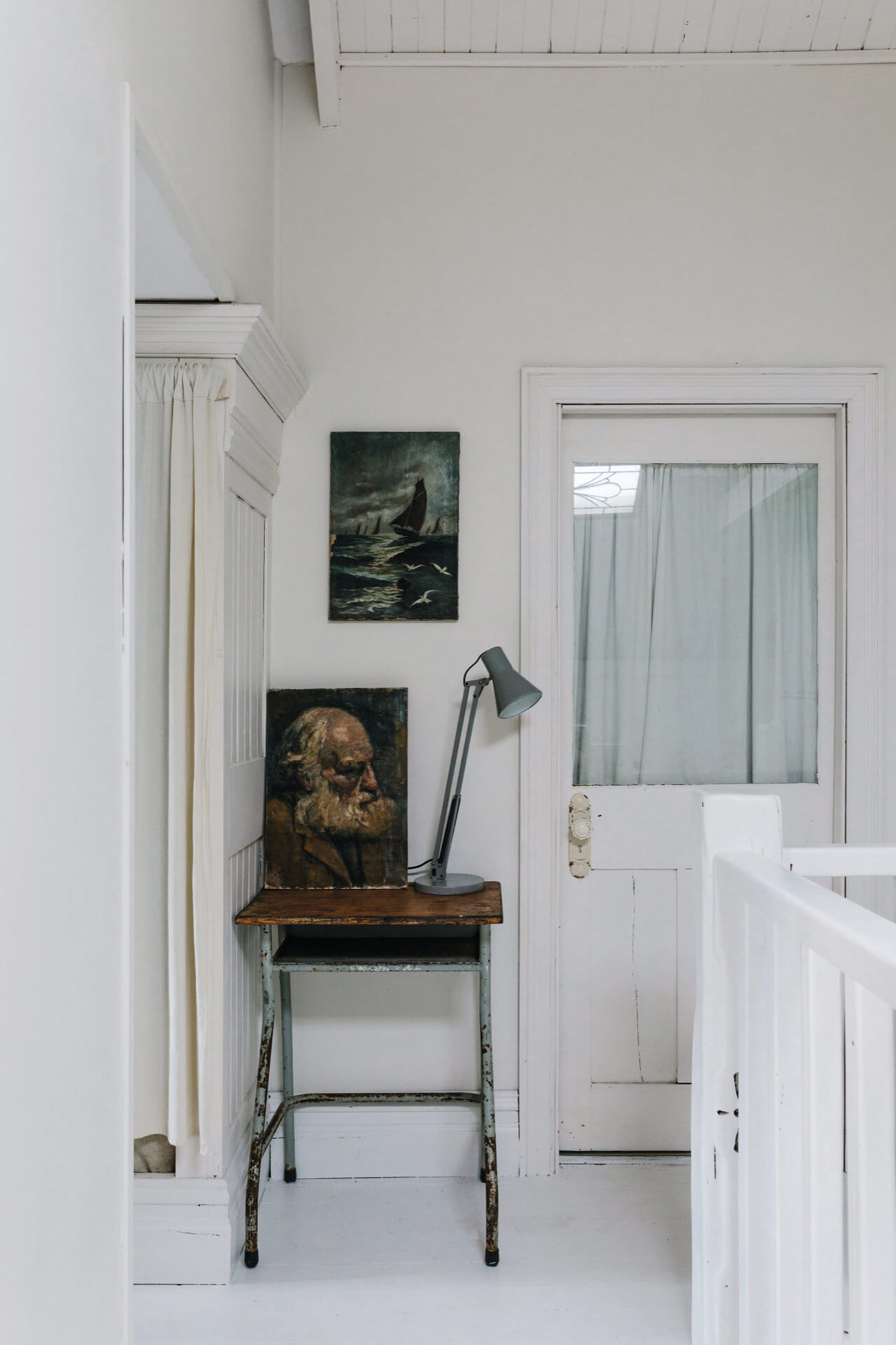a white interior with vintage furniture and a vintage portrait
