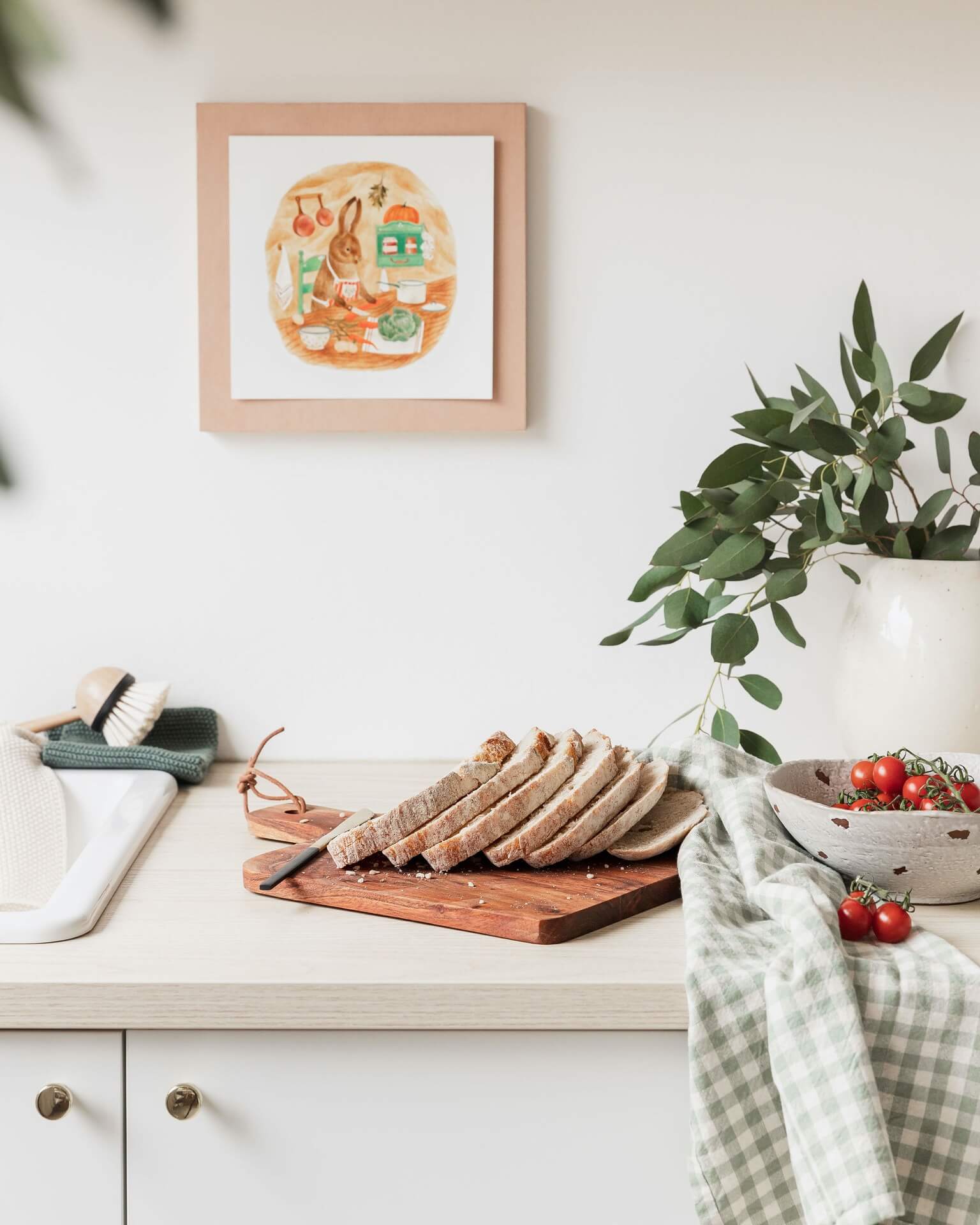 Kitchen worktop with bread board and Ochre cushion on a bed and other items from lifestyle store Tusk