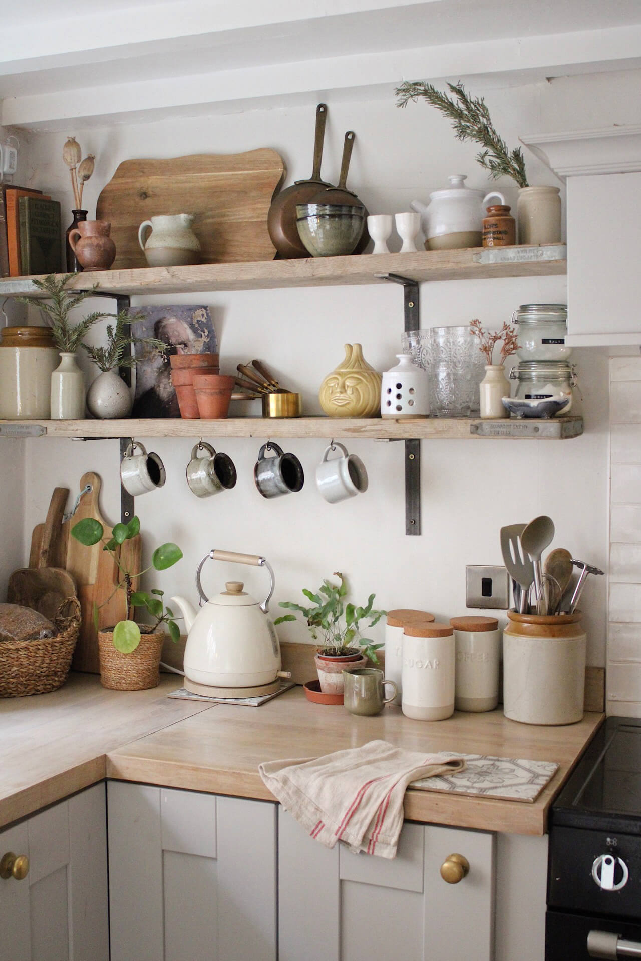 Home tour with Rachel Ashfield of @the_old_cottage - a corner of the kitchen with reclaimed wooden shelving filled with vintage kitchenalia. 