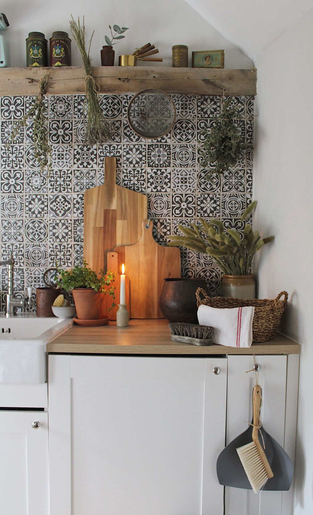 Home tour with Rachel Ashfield of @the_old_cottage - a corner of the ktichen with patterned wall tiles, reclaimed wooden shelving and vintage decorative items