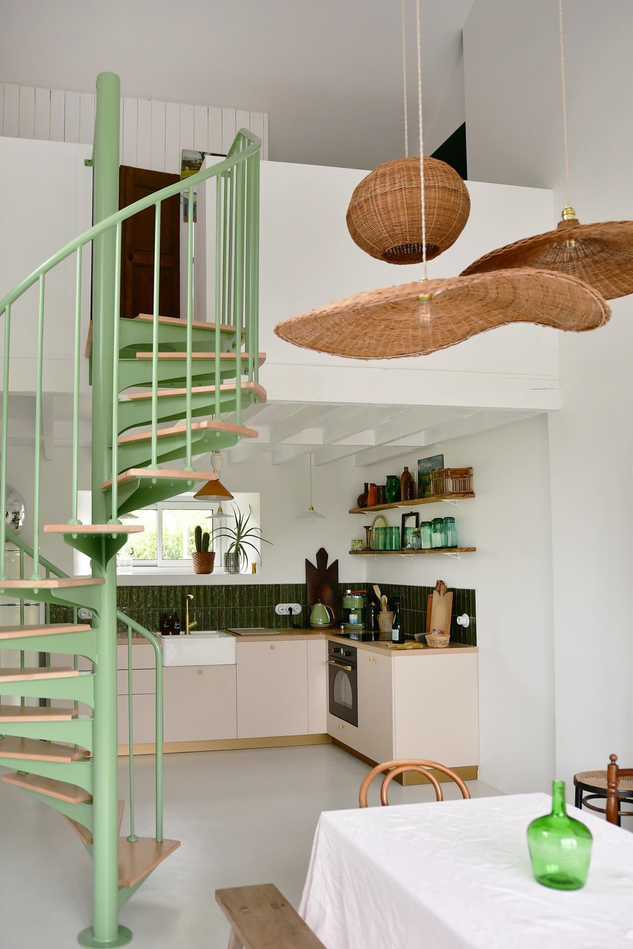 a mint green spiral staircase runs up through a white interior, decorated with vintage finds. 
