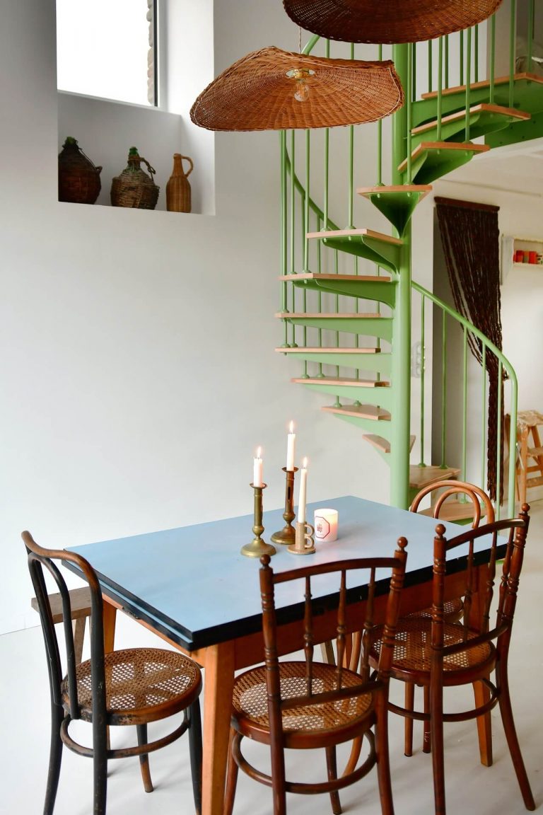 Vintage dining table and a mint green spiral staircase in a white interior